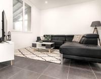 a living room with a black couch and a table at Chambre qualité hôtel 4 etoiles dans un appartement partagé in Frouzins