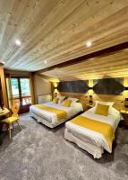 2 Betten in einem großen Zimmer mit Holzdecken in der Unterkunft Hameau des Prodains - Hôtel in Morzine