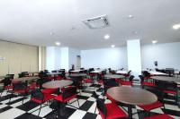 an empty room with tables and red chairs at Hotel Sutha Inn Syariah in Jambi