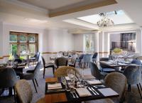 um restaurante com mesas e cadeiras e um lustre em Delta Hotels by Marriott Breadsall Priory Country Club em Derby