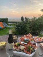 a table with a plate of seafood and a bottle of wine at Manava Villa vue mer et Mont Saint Michel piscine intérieure in Saint-Jean-le-Thomas