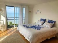 a bedroom with a large bed and a large window at Manava Villa vue mer et Mont Saint Michel piscine intérieure in Saint-Jean-le-Thomas