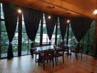 two tables and chairs in a room with large windows at Porto Gumati in Kutaisi