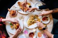 eine Gruppe von Menschen sitzt um einen Tisch herum und isst in der Unterkunft The Hoxton Lloyd Amsterdam City Centre East in Amsterdam