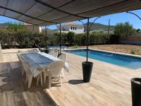 einen Tisch und Stühle unter einem Baldachin neben einem Pool in der Unterkunft Villa Andrée avec piscine à proximité de la mer in Saint-Cyr-sur-Mer