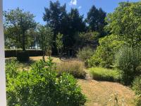 a garden with bushes and trees in the background at Les Beaux Sapins 2 in Rochechouart