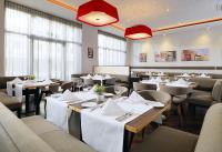 a restaurant with white tables and chairs and windows at Novotel Nürnberg Centre Ville in Nürnberg