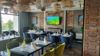 a dining room with tables and chairs and a tv at Hotel Kőporos Hercegkút in Hercegkút