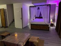 a room with a bed and a table and purple lighting at La Paillote Exotique Spa in Beaucaire