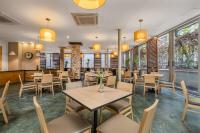 a restaurant with tables and chairs and windows at Novelty Suites Hotel - Oviedo Mall in Medellín