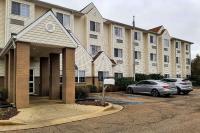 Un gran edificio con coches aparcados en un estacionamiento. en Starkville Inn &amp; Suites, en Starkville