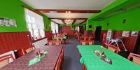 um restaurante com paredes verdes, mesas e cadeiras em motorest U KONĚ em Kamenický Šenov