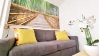 a couch with two yellow pillows in a living room at Le Ptit Paradis - Calme - Wifi - Cour privée - Relax BNB in Mulhouse