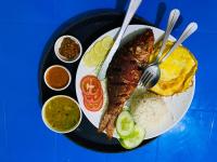 a plate of food with fish and rice and different sauces at The Lumbini Hotel & Restaurant in Lumbini