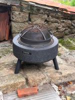 a stove sitting on the ground next to a stone wall at Gîte les Pieds dans l&#39;eau bord de Sèvre, 10 min du Puy du Fo in Treize-Vents