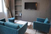 a living room with two blue chairs and a tv at Les Suites Massena in Nice