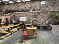a restaurant with wooden tables and chairs and a stone wall at Le Refuge du Rempart in Dambach-la-Ville