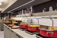una linea di buffet con tanto cibo in pentole rosse di Amedia Hotel Milan, Trademark Collection by Wyndham a Milano
