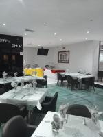 ベイラにあるHotel Embaixadorの白いテーブルと椅子、ステージのあるダイニングルーム