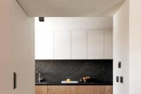 a kitchen with white cabinets and a black counter top at Appartement Rémy - at the foot of the slopes in Saint-Gervais-les-Bains