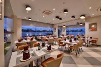 Un restaurante con mesas, sillas y ventanas. en Click Hotel Pithampur, en Mhow