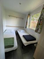 two beds in a small room with a window at Mobilehome climatisé avec TV pour 4 à 6 personnes in Boofzheim