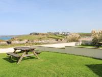 a picnic table sitting on the grass near the ocean at The Beach House in Newquay