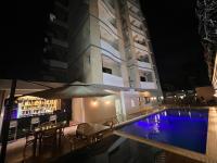 a swimming pool with an umbrella and chairs and a building at Hotel Golf Coast in Kinshasa