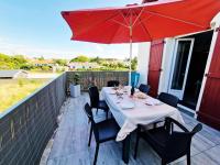a table with a red umbrella on a patio at Charmant duplex à 500 m de la plage in Barbâtre