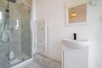 La salle de bains blanche est pourvue d&#39;un lavabo et d&#39;une douche. dans l&#39;établissement Le Chic de Medreville * Nancy, à Nancy