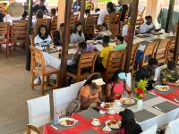 a group of people sitting at tables in a restaurant at Hans Cottage Botel in Cape Coast