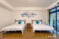 two beds in a room with white walls and wood floors at Promised Land B&amp;B in Taitung City