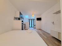 a white bedroom with a large bed and a kitchen at Maputo - Appartement climatisé in Reims