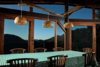 a dining room with a table and chairs and windows at Eco Lodge de Construção Natural com Vista Panorâmica in Nova Friburgo
