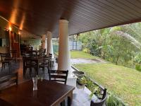 Un restaurante con mesas y sillas y un gran ventanal. en Eagles Eco Lodge - Kandy, en Digana
