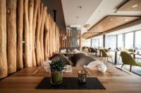 comedor con mesa y sillas y pared de troncos en Kulmberghaus Resort, en Saalfeld