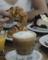 a person eating a pastry on a table with plates of food at Hotel Plaza in Colón