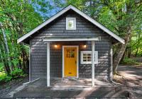 a tiny house with a yellow door in the woods at Sunwolf Riverside Cabins in Brackendale