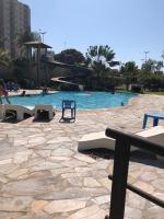 a swimming pool with a bench and people in the water at Golden Dolphin Express in Caldas Novas