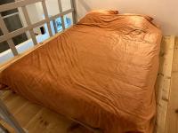 a bed with an orange comforter sitting on the floor at Antwerp West Side in Zwijndrecht