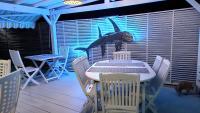 a table and chairs on a deck with a blue light at La Rose du Bresil Marie-Galante in Capesterre