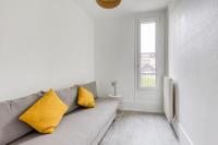 a white living room with a gray couch with yellow pillows at Appartement entier au coeur de Nogent Sur Marne in Nogent-sur-Marne