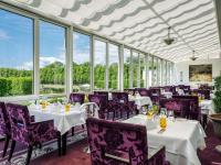 a restaurant with white tables and purple chairs and windows at Parkhotel Bremen – ein Mitglied der Hommage Luxury Hotels Collection in Bremen