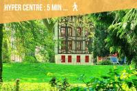 a large building with red doors in a green park at Le Lovely cosy jacuzzi centre-ville wifi in Rouen