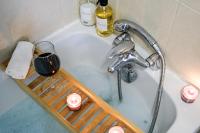 a bath tub with a glass of wine and a shelf at Numéro 6 - Place Nationale - Wifi et Fibre in Montauban