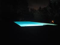 a pool lit up at night with blue lights at Lou mas del ranc in Roquestéron