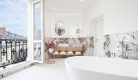 a white bathroom with a tub and a large window at Grand Hôtel Du Palais Royal in Paris