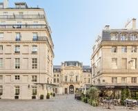 a group of buildings with tables and chairs in a courtyard at Grand Hôtel Du Palais Royal in Paris