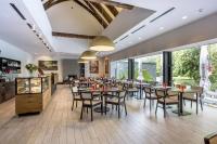 um restaurante com mesas e cadeiras e grandes janelas em Yard Resort em Předboj