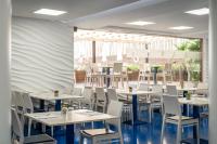 een eetkamer met witte tafels en stoelen bij ALEGRIA Sun Village in Lloret de Mar